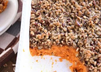 Scoop taken out of sweet potato casserole in white baking dish.