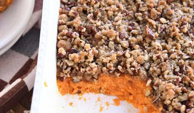 Scoop taken out of sweet potato casserole in white baking dish.