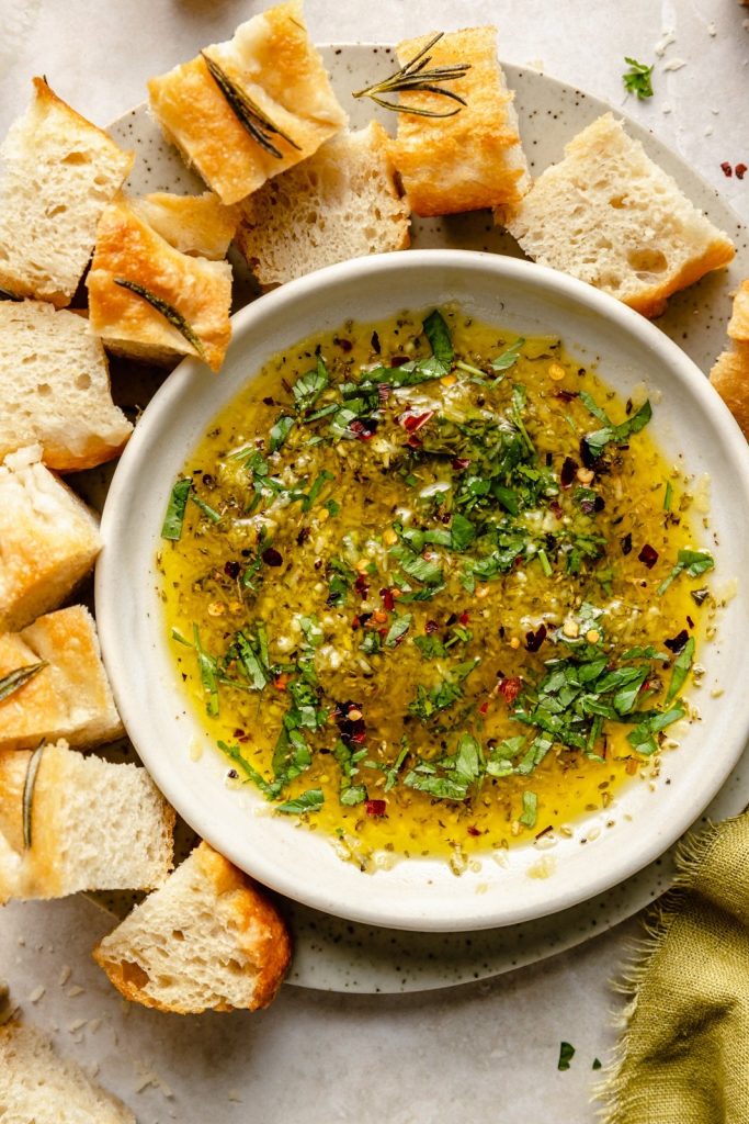 homemade olive oil dip in a bowl surrounded by cubed bread