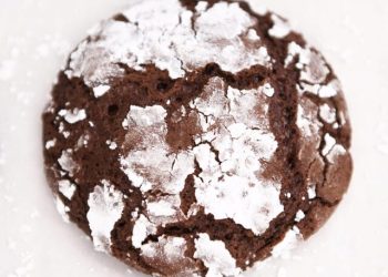 Chocolate crinkle cookie on parchment paper.