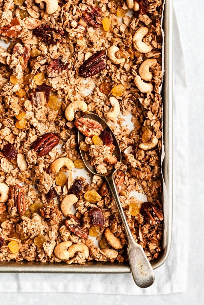 homemade chunky healthy granola on a baking sheet with a spoon