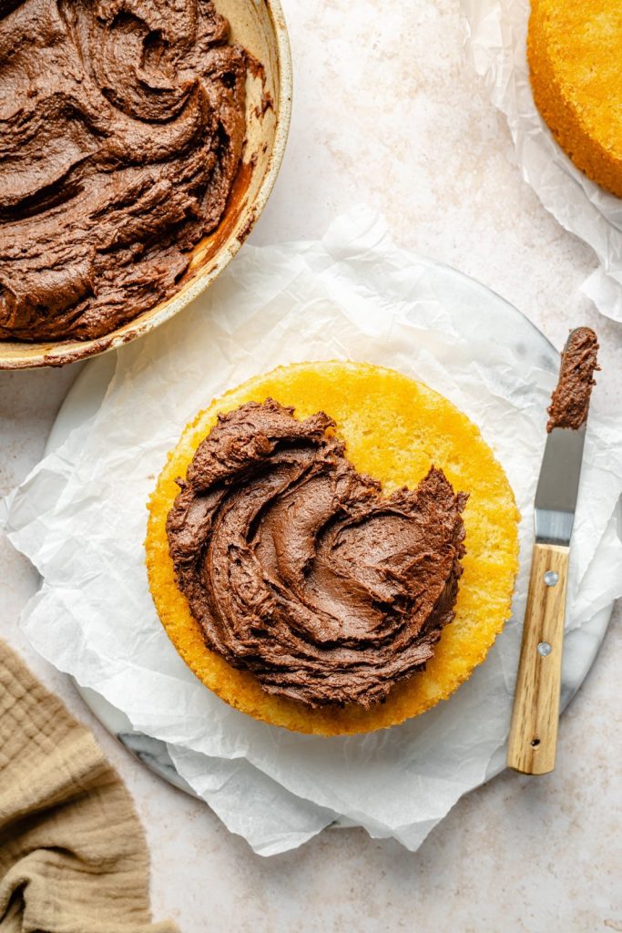 chocolate buttercream frosting spread on yellow cake layers