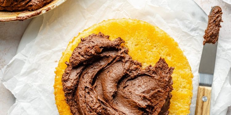 chocolate buttercream frosting spread on yellow cake layers
