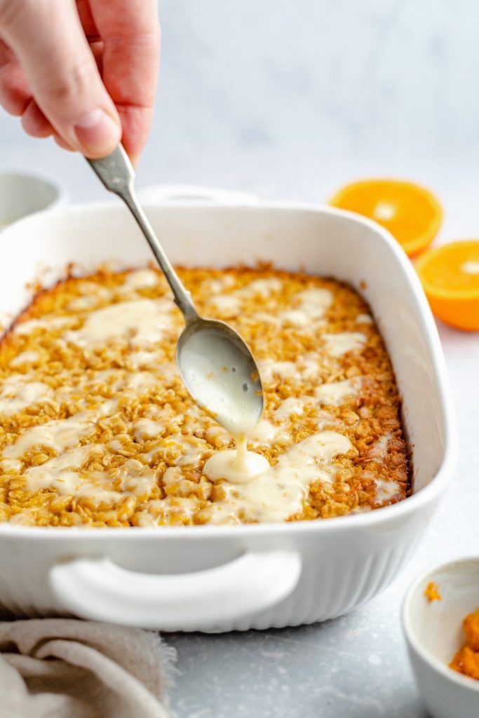 drizzling an orange oatmeal bake with glaze