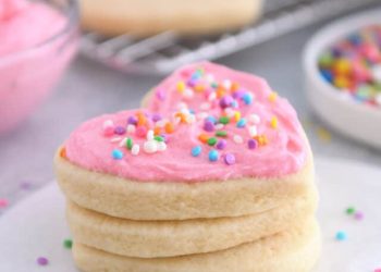 Heart shaped sugar cookie with pink frosting and sprinkles.