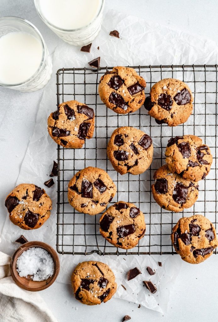 paleo chocolate chip cookies on a wire rack next to two glasses of milk