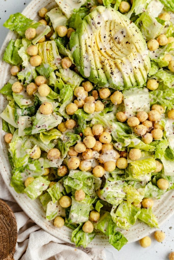 vegan caesar salad with chickpeas and avocado on a platter