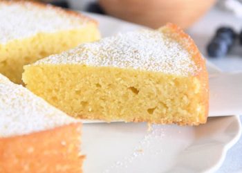 Triangle of olive oil cake on white cake server.