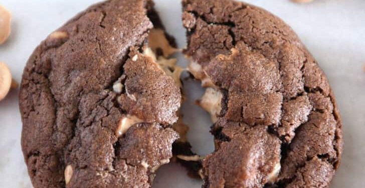 One chocolate cookie pulled in half with melty peanut butter chips.