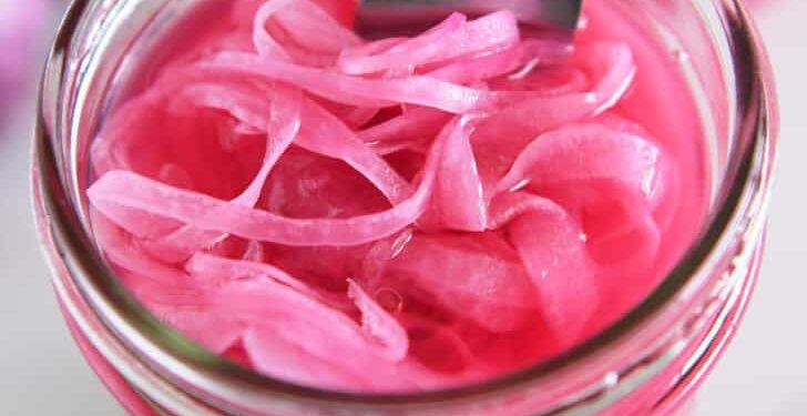 Top down view of fork in jar with pickled red onions.