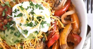 Top down view of white shallow bowl with chicken, vegetables, cheese, sour cream and guacamole.