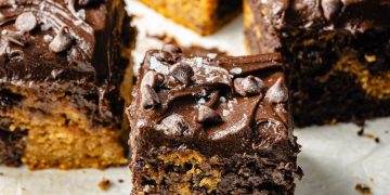 marbled pumpkin cake with chocolate frosting cut into square pieces
