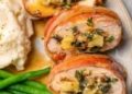 Plate with prosciutto-wrapped stuffed turkey tenderloin, green beans, and mashed potatoes.