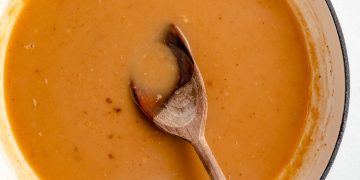 homemade turkey gravy in a pot with a wooden spoon