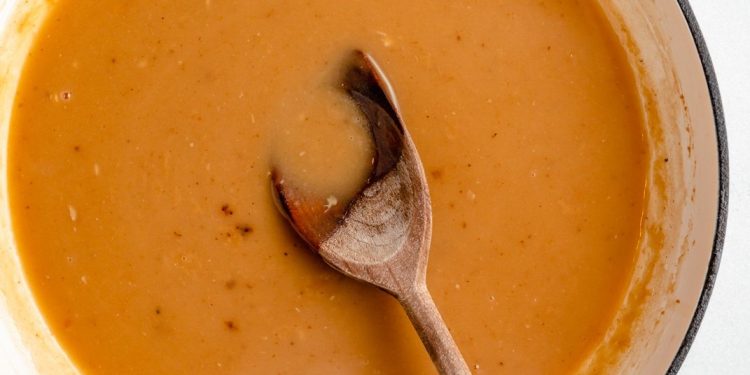homemade turkey gravy in a pot with a wooden spoon